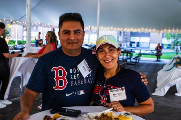 Two alumni smile for the camera while wearing their Red Sox gear at the Wentworth at the Red Sox event in 2021