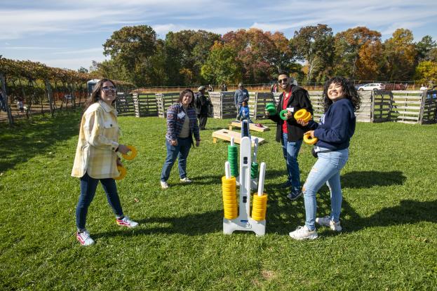 A group of young alumni play a giant game of Connect Four at the Alumni & Family Apple Picking Outing