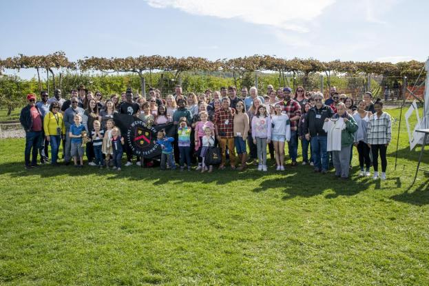 The entire group of alumni and their families pose at the Alumni & Family Apple Picking Outing
