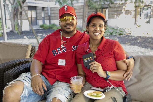 Two alumni wearing all red pose on the quad at the Red Sox event