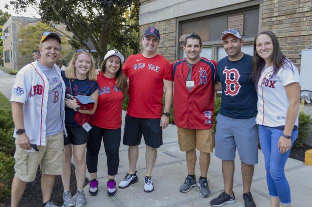 A group of alumni smile while wearing Red Sox jerseys on the quad