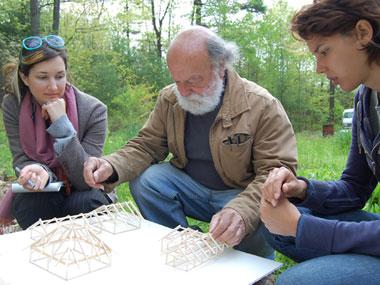 A man with two students reviewing models of architecture
