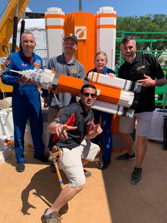 A group of people holding a model rocket